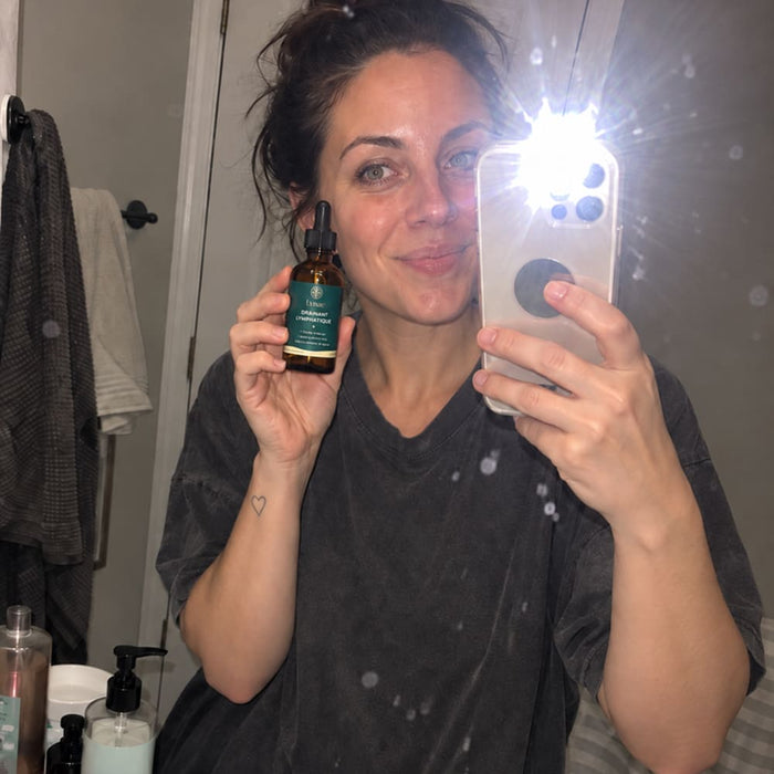 Cliente tenant le flacon Lynae devant son miroir